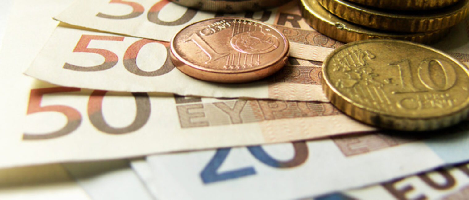 Euro-Geldscheine und Cent-Münzen liegen aufeinander.
