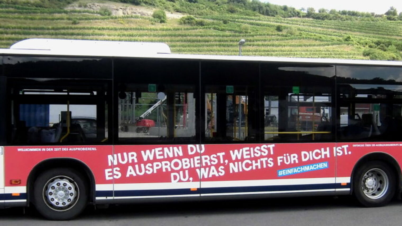 Ein Linienbus, der mit Werbung für das Handwerk in rot und blau beklebt ist.