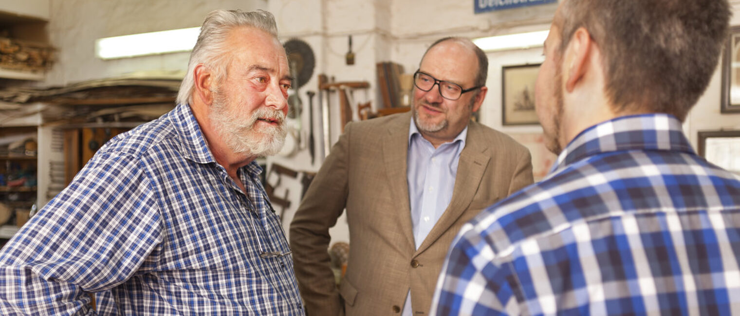 Drei Männer unterhalten sich in einer Werkstatt