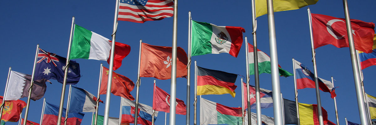Im Auslandsgeschäft liegen große Chancen für Handwerksbetriebe. viele bunte Landesflaggen flattern im Wind vor blauem Himmel