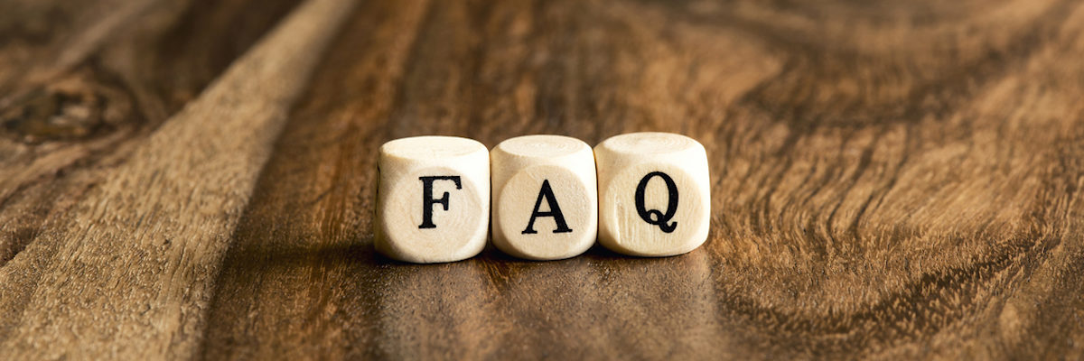 Häufig gestellte Fragen Auf einem Holztisch liegen drei Würfel mit den Buchstaben FAQ.