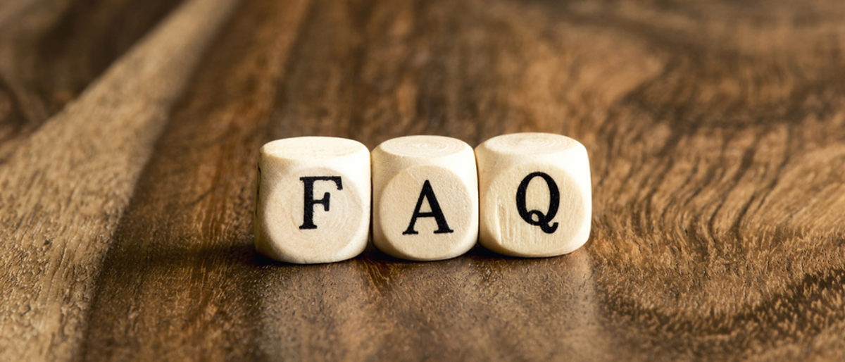 Häufig gestellte Fragen Auf einem Holztisch liegen drei Würfel mit den Buchstaben FAQ.