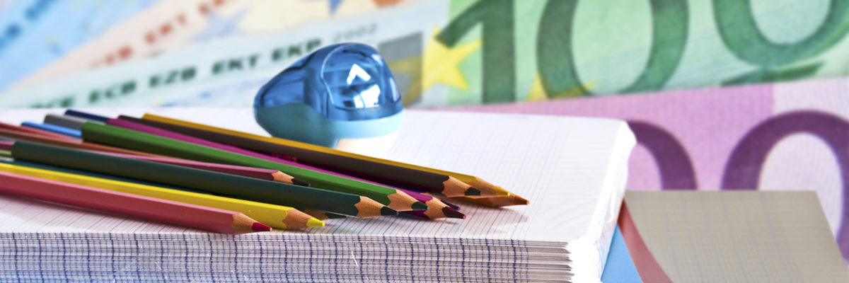 Mit einem Stipendium können Handwerker die Weiterbildung finanzieren. Buntstifte und Spitzer liegen auf einem Block Papier. Im Hintergrund sind Euroscheine zu erkennen.