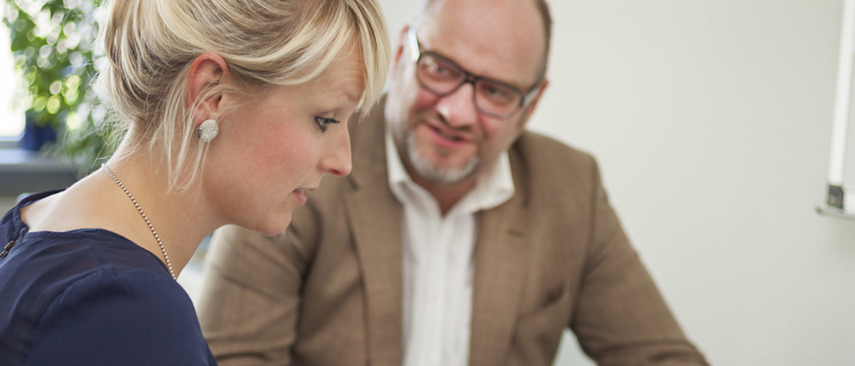 Individuelle Beratung für Gründer und Unternehmer im Handwerk. Ein Mann und eine Frau sitzen zusammen am Tisch. Der Mann spricht und schaut die Frau dabei an.