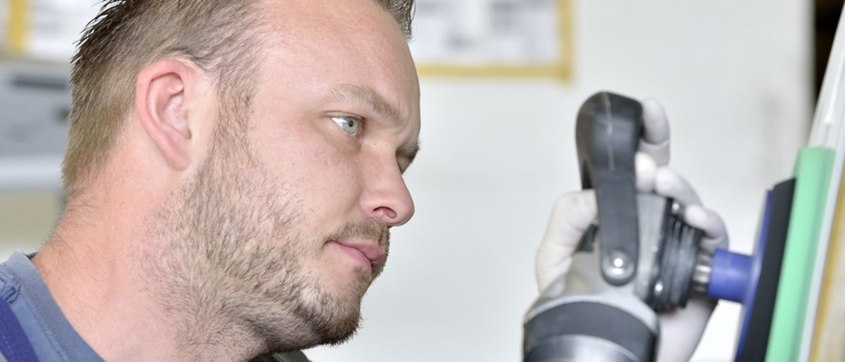 Karosserie- und Fahrzeugbaumechaniker ist ein Handwerksberuf mit Zukunft. Ein Mann in blauer Arbeitskleidung bearbeitet eine Oberfläche mit einem Poliergerät.