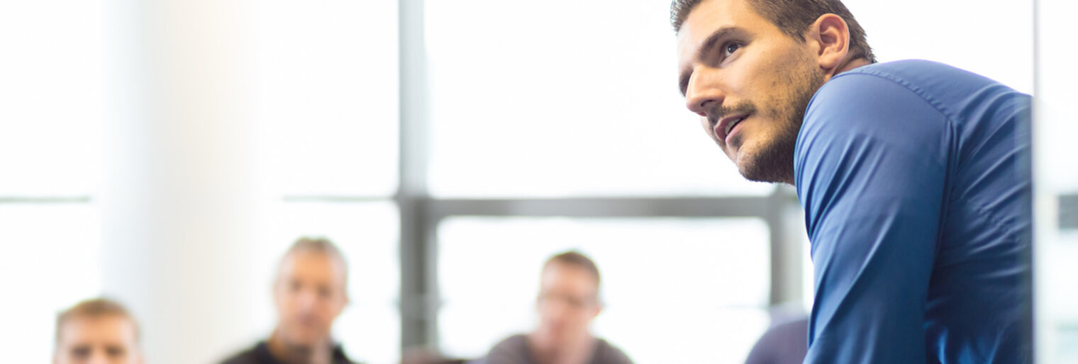 Dozent präsentiert vor drei Männern