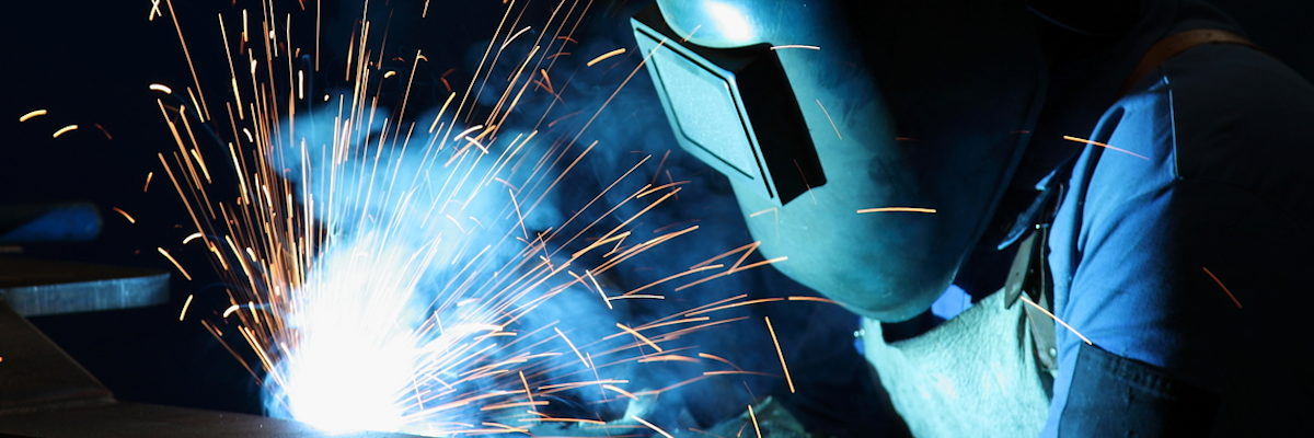 Beschäftigte müssen vor arbeitsbedingten Gefährdungen geschützt werden Metallbauer trägt Schutzbrille beim Schweißen mit Funkenflug