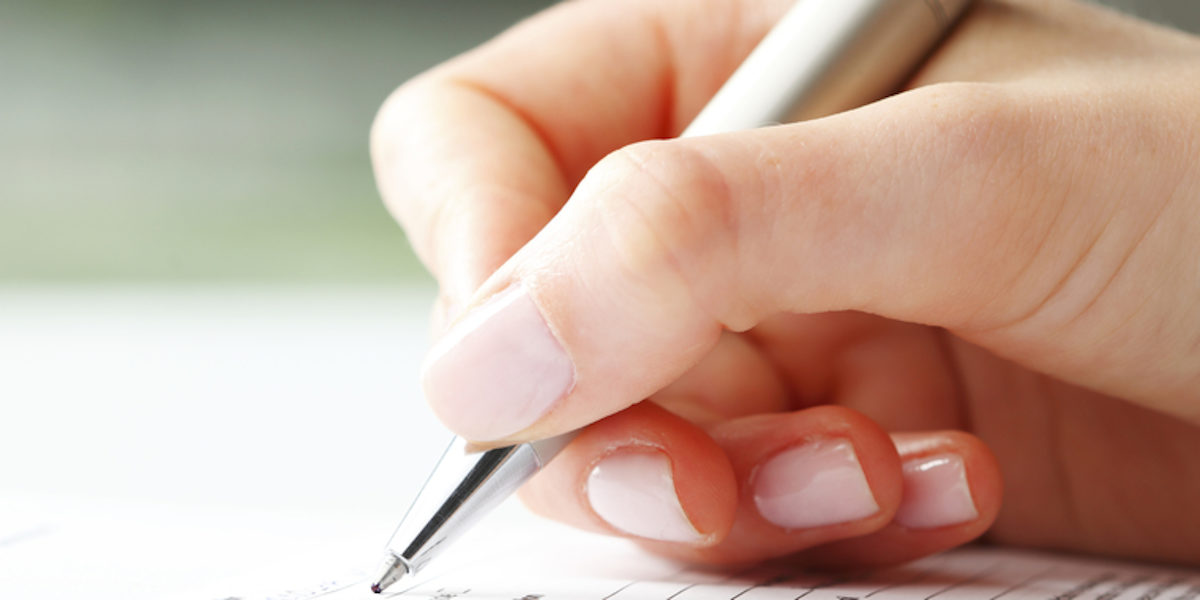 Eine Frauenhand schreibt mit einem Kugelschreiber.