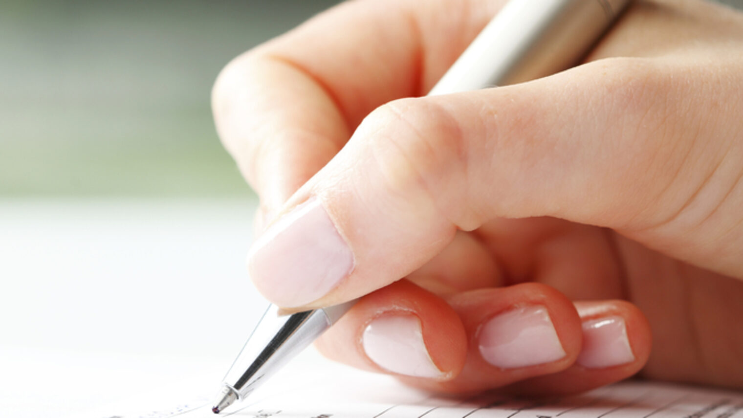 Eine Frauenhand schreibt mit einem Kugelschreiber.