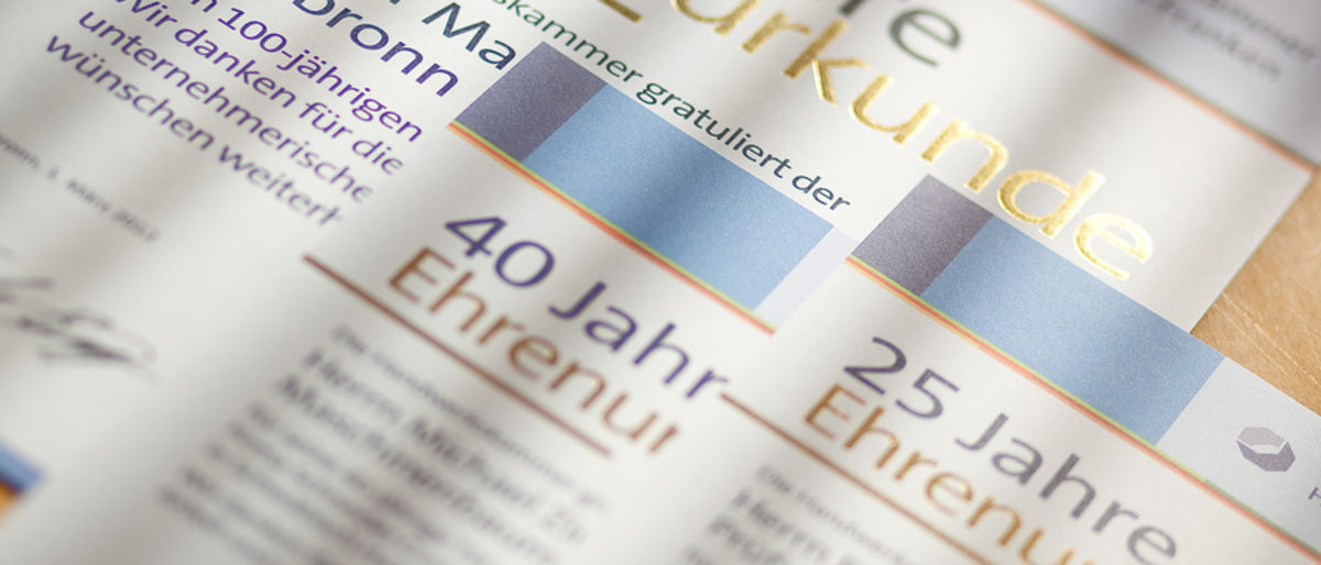 Betriebe können Ehrenurkunden für ein Betriebs- oder Mitarbeiterjubiläum online beantragen. Mehrere Ehrenurkunden der Handwerkskammer liegen auf einem Tisch.