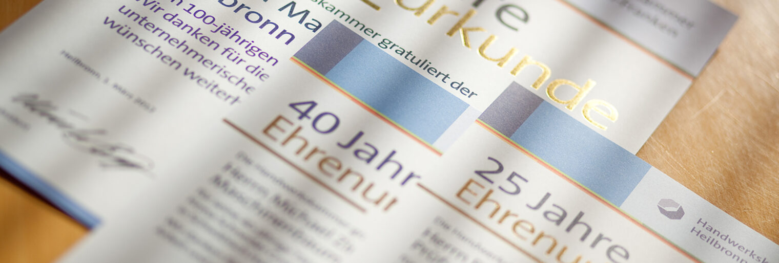 Mehrere Ehrenurkunden der Handwerkskammer liegen auf einem Tisch.