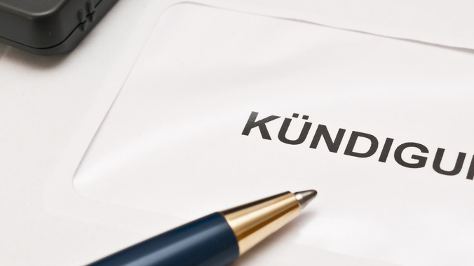 Ein Blatt mit der Aufschrift "Kündigung" . Darauf liegt ein dunkler Kugelschreiber.