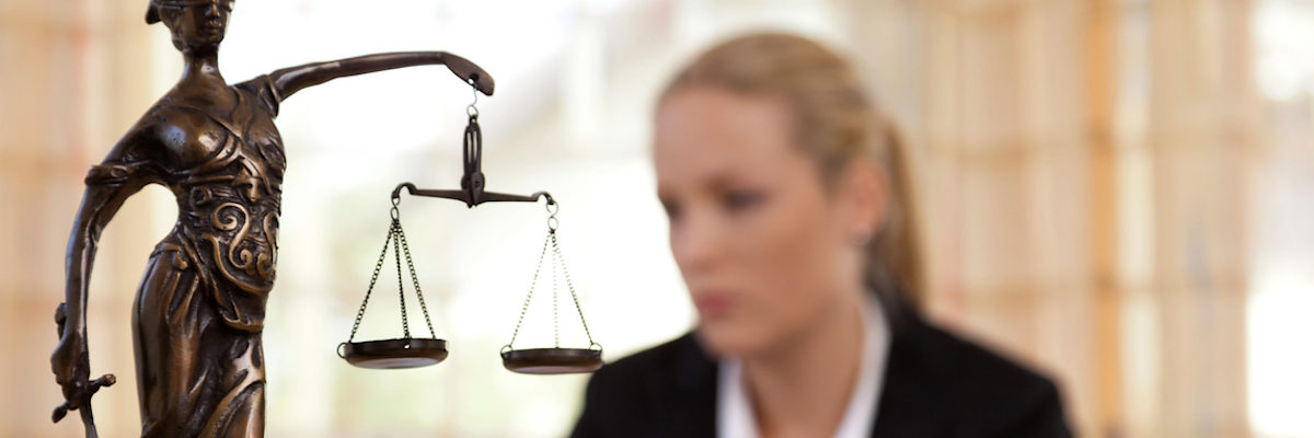 Mitgliedsbetriebe erhalten Rechtsberatung bei der Handwerkskammer. Eine Bronzefigur der Justitia im Vordergrund. Dahinter ist verschwommen eine Frau zu sehen.