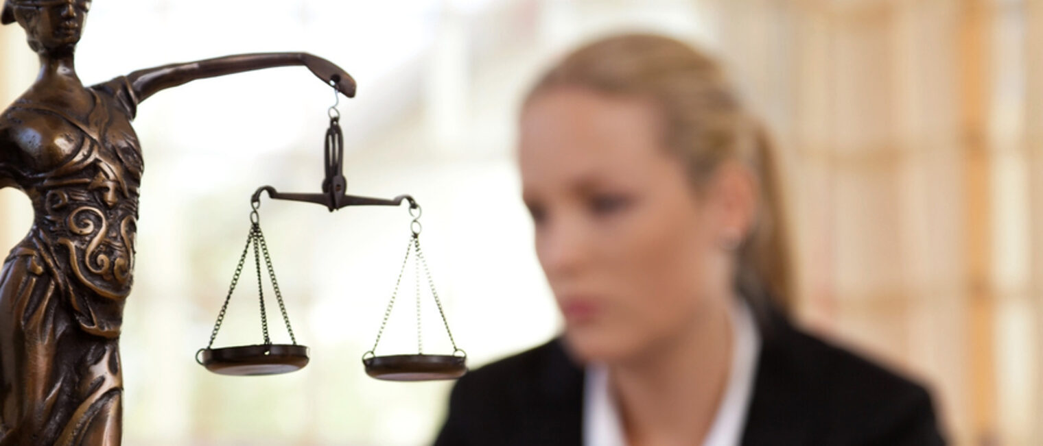 Mitgliedsbetriebe erhalten Rechtsberatung bei der Handwerkskammer. Eine Bronzefigur der Justitia im Vordergrund. Dahinter ist verschwommen eine Frau zu sehen.