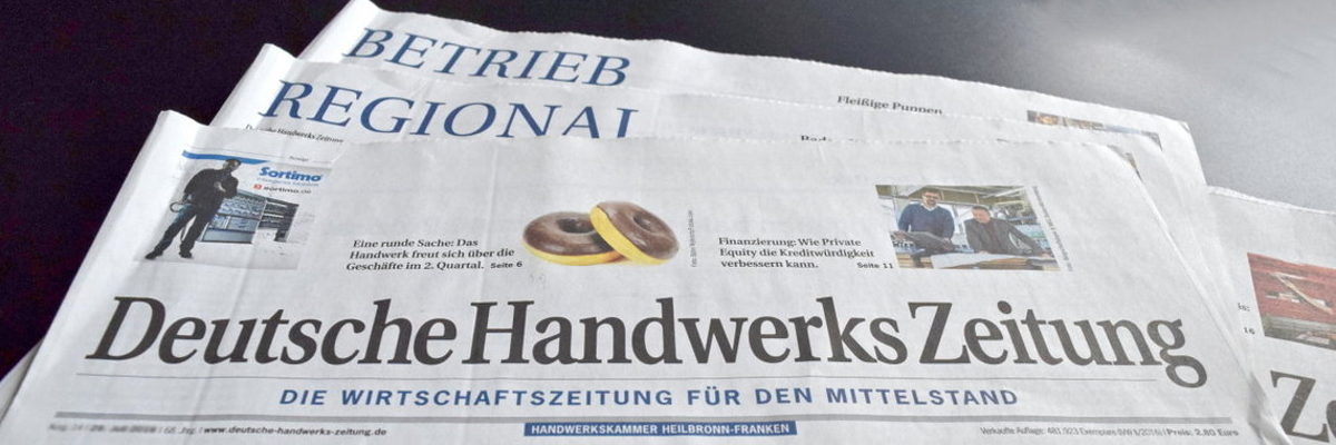 Die Deutsche Handwerks Zeitung informiert die Leser aus dem Handwerk. Einige Blätter der Deutschen Handwerks Zeitung liegen auf einem schwarzen Untergrund.