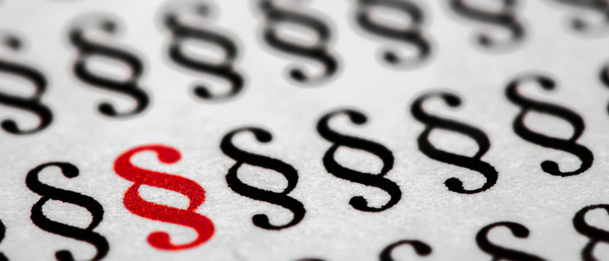 Rechtsvorschriften Paragraphen-Zeichen in Schwarz und eines in rot stehen auf einem Blatt in mehreren Zeilen.