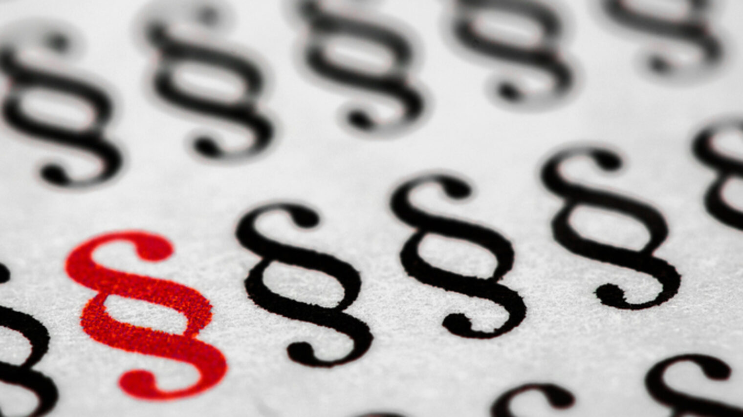 Paragraphen-Zeichen in Schwarz und eines in rot stehen auf einem Blatt in mehreren Zeilen.