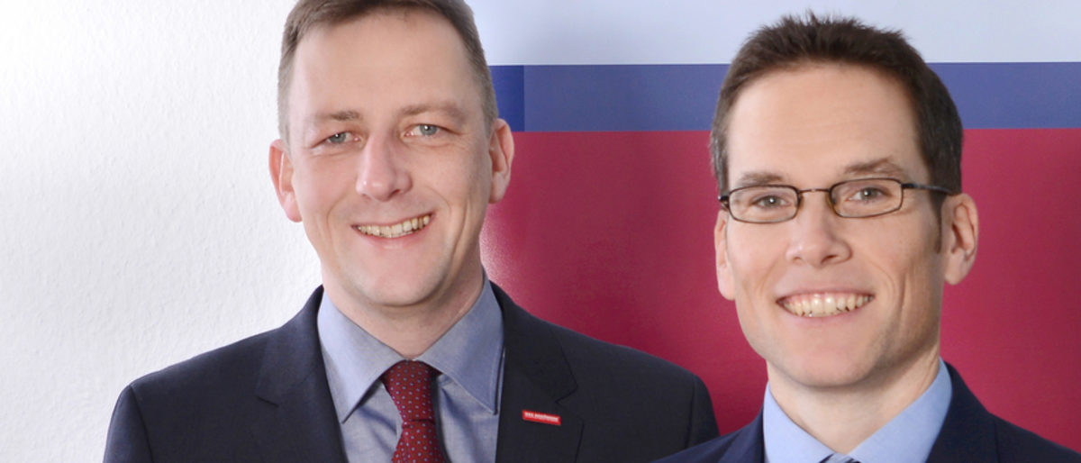 Hauptgeschäftsführer Ralf Schnörr (l.), Stellvertreter Achim Hofmann. Zwei Männer lächeln in die Kamera. Nur Ihre Köpfe, Hals und Schultern sind zu sehen. Sie tragen Sakko, Hemd und Krawatte.