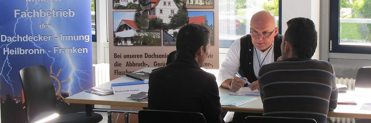 Dachdeckermeister Kurt Breischaft im Gespräch mit zwei Flüchtlingen.
