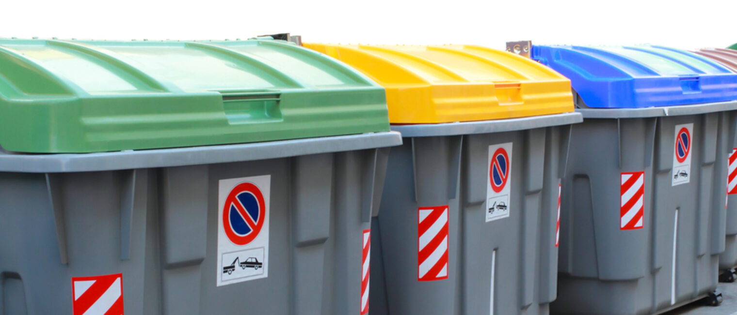 Mehrere große Recycling Müllcontainer mit grünen, gelben und blauen Deckel