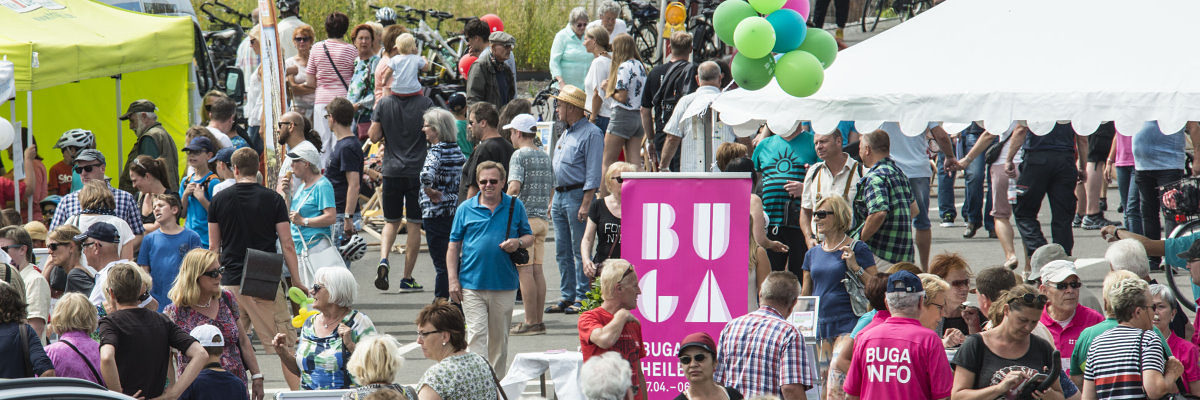 Die Bundesgartenschau 2019 in Heilbronn können auch Handwerker nutzen. Viele Menschen sind zwischen Informationsständen unterwegs. In der Mitte ist ein pinkfarbenes Schild mit Aufschrift "BUGA".