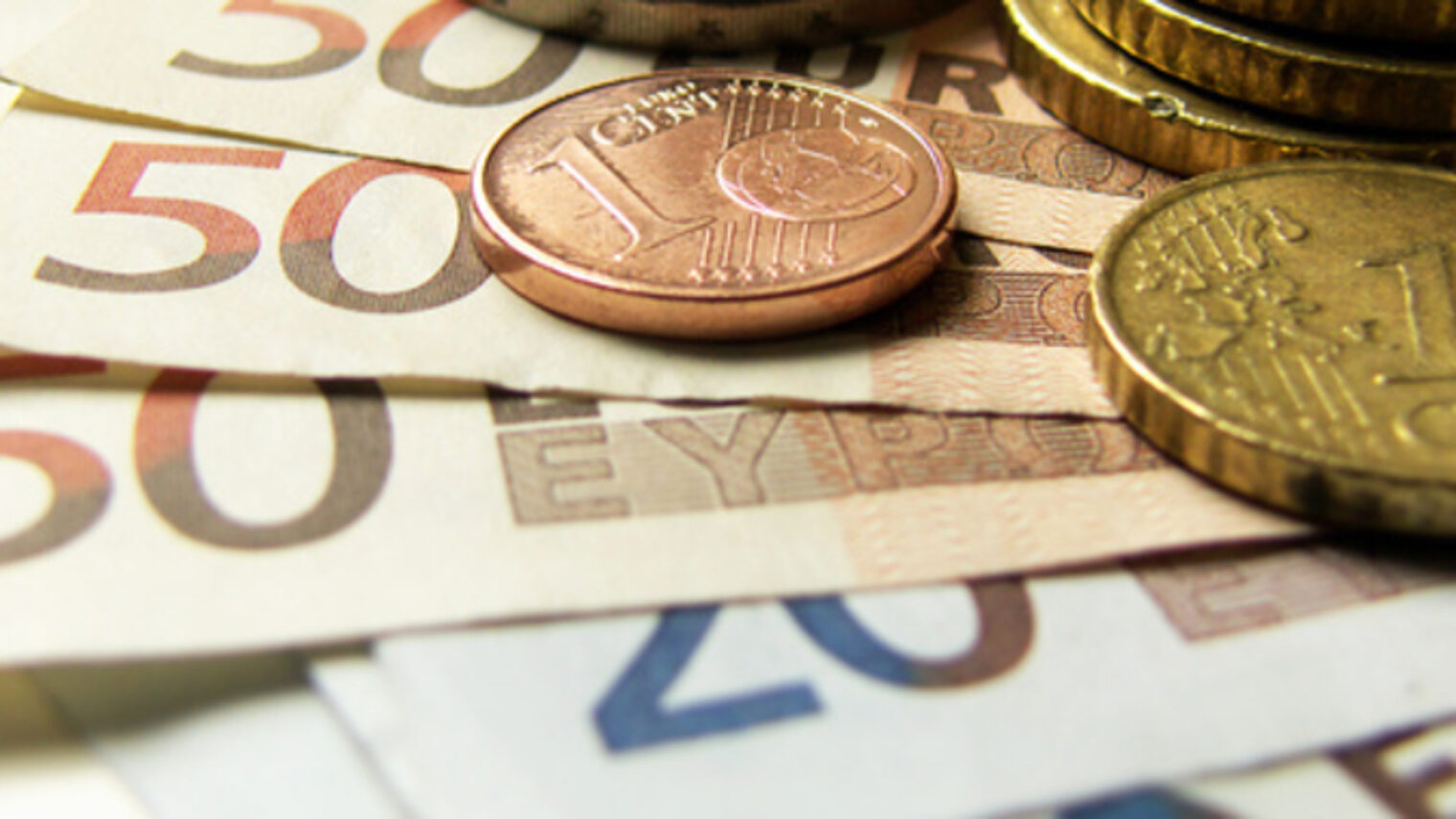 Euro-Geldscheine und Cent-Münzen liegen aufeinander.