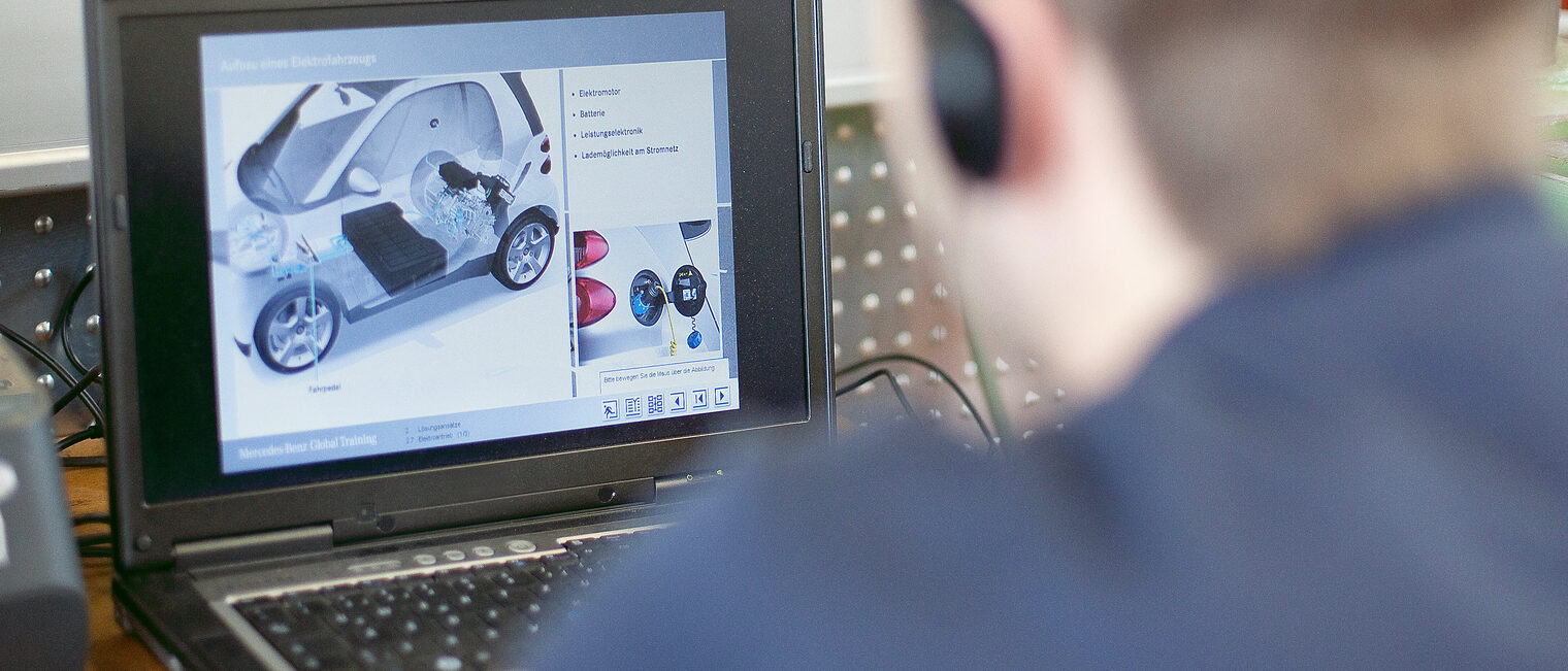 Digitalisierung im Handwerk. Junger Mann mit Kopfhörern sitzt vor einem Bildschirm.