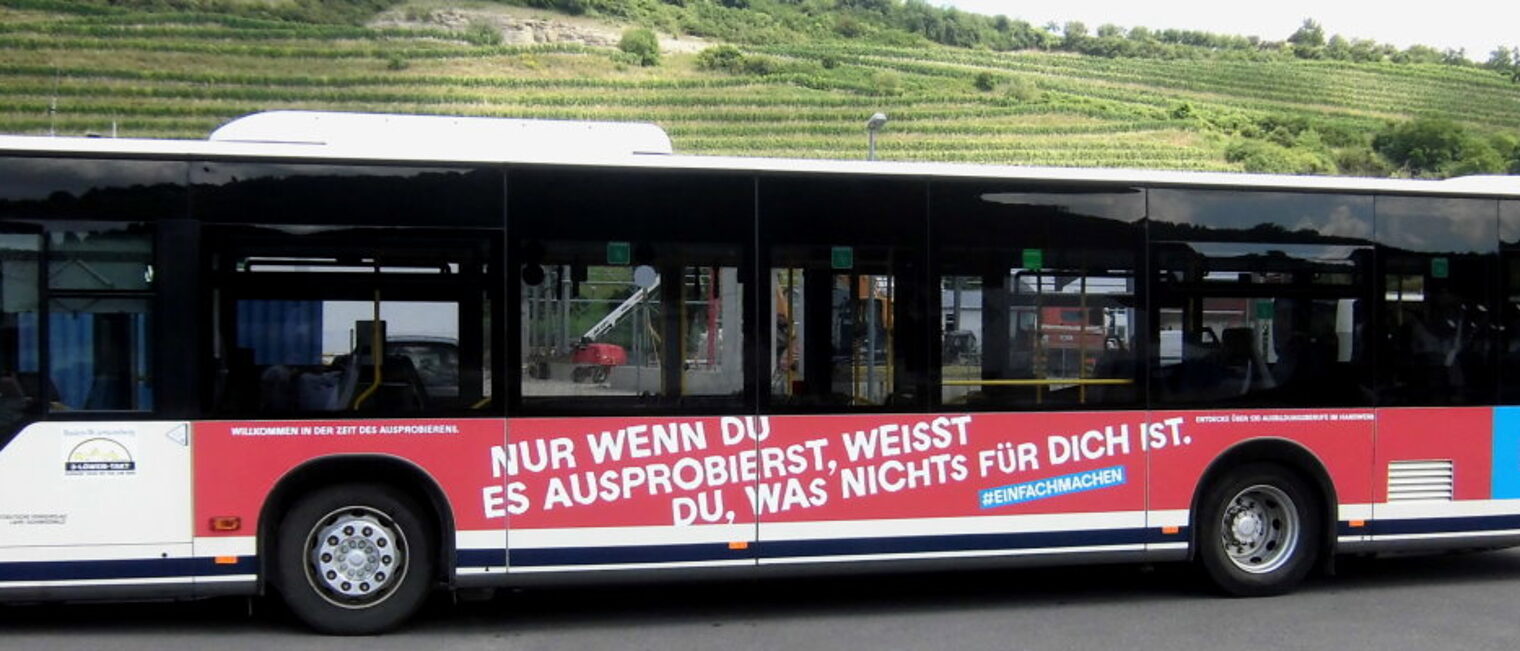 Ein Linienbus, der mit Werbung für das Handwerk in rot und blau beklebt ist.