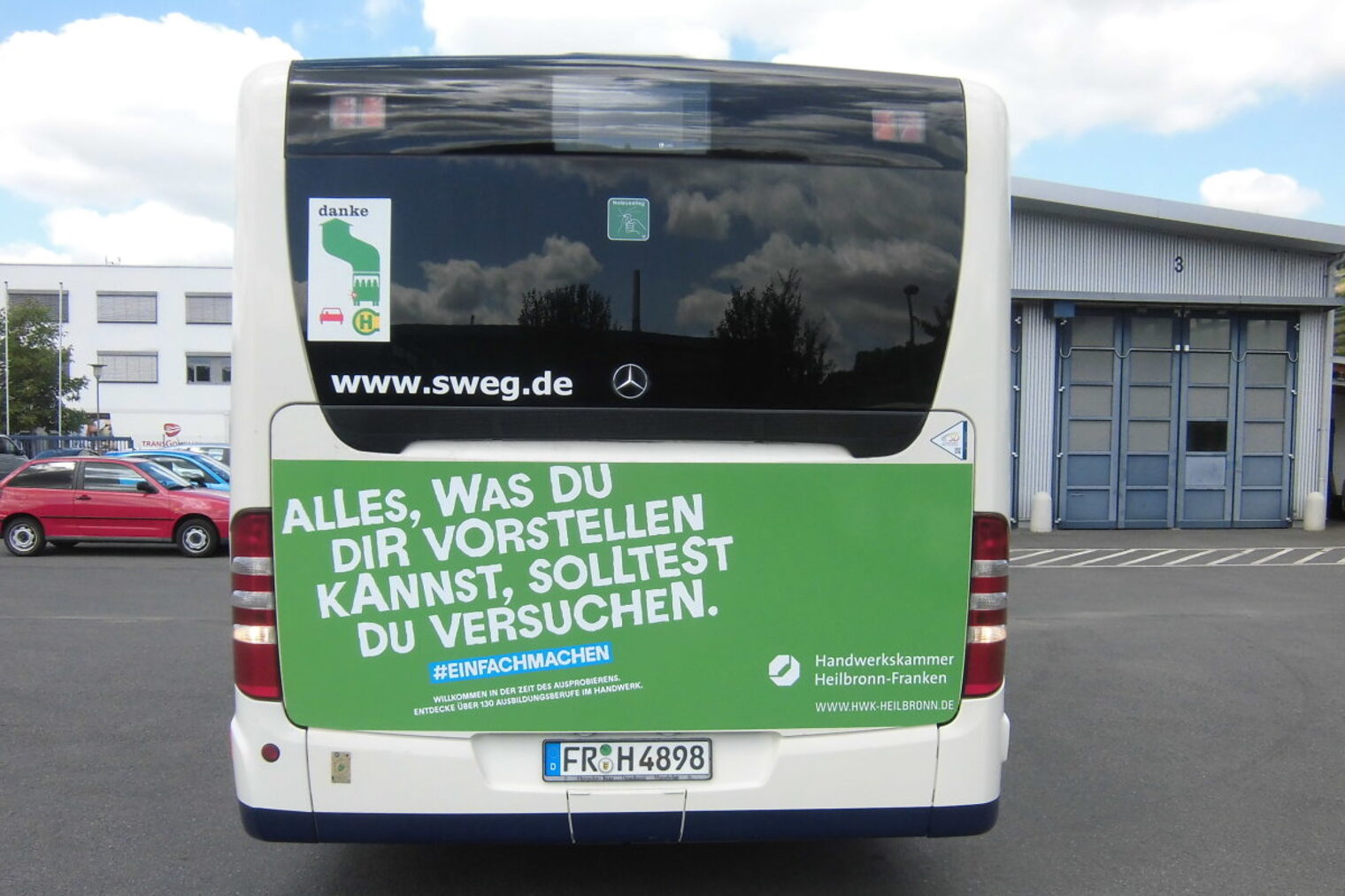 Rückseite eines Busses, beklebt mit grüner Folie mit den Spruch "Alles was du dir vorstellen kannst, solltest du versuchen".