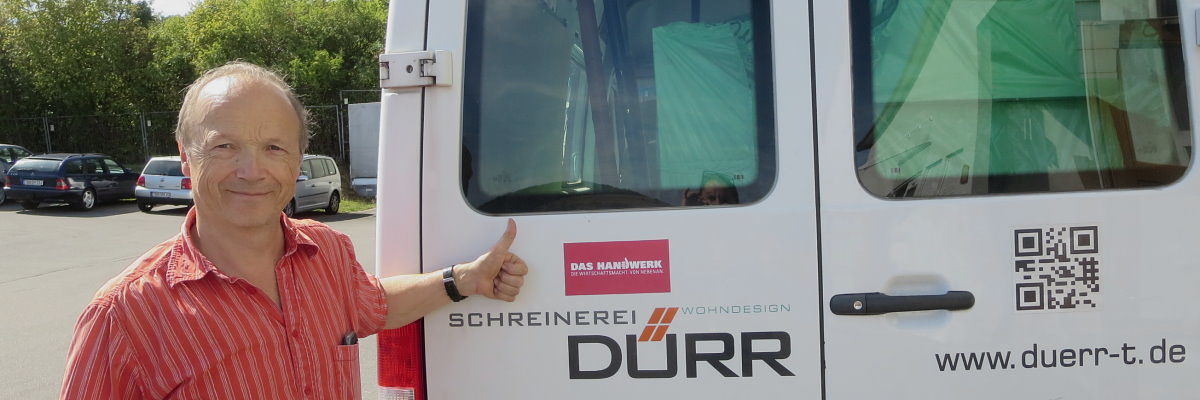 Die Schreinerei Dürr zeigt wie es geht und ist beim Gewinnspiel dabei. Mann steht vor einem Transporter mit einem roten Aufkleber des Schriftzugs "Das Handwerk" und macht eine "Daumen-hoch"-Geste.