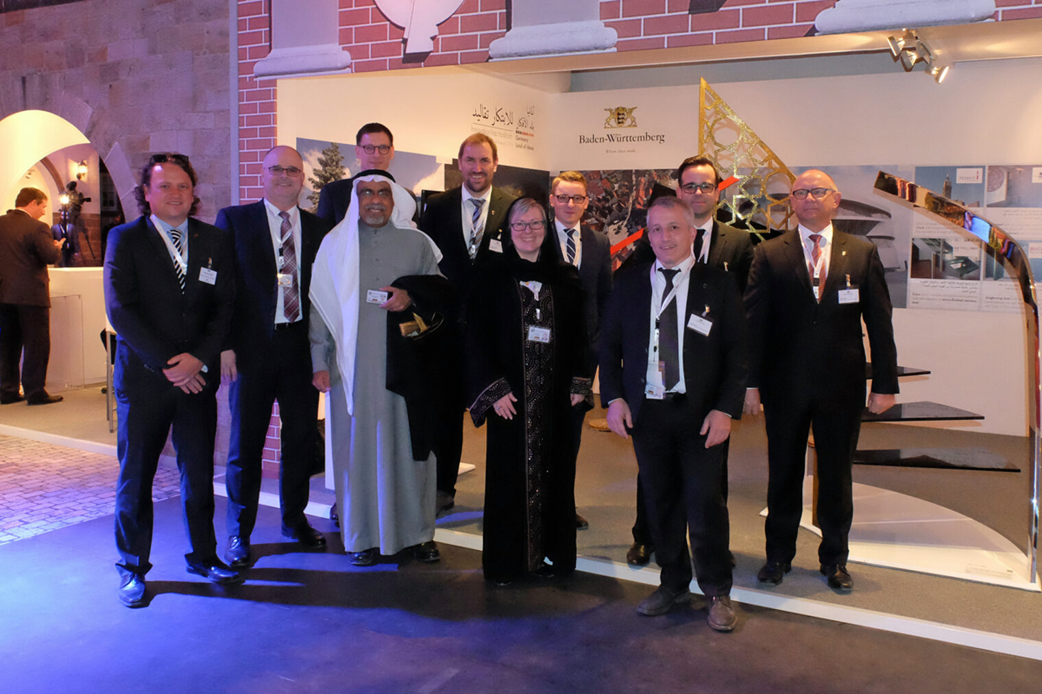 Eine Gruppe von Menschen gemischter Nationalitäten stehen versammelt auf einem Messestand.