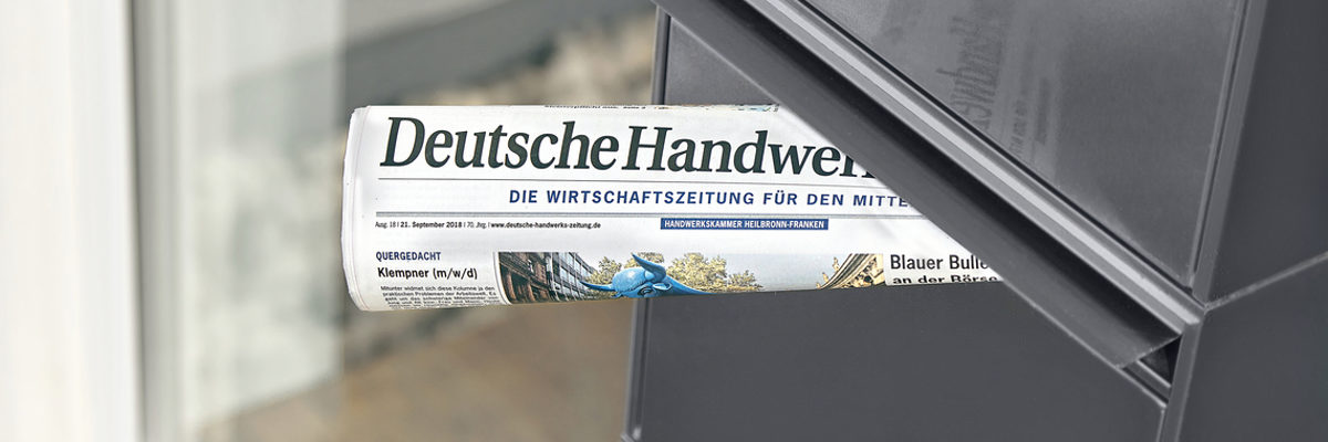 Eine neue Ausgabe der Deutschen Handwerks Zeitung ist erschienen. Eine zusammengerollte Ausgabe der Deutschen Handwerks Zeitung steckt in einem grauen Briefkasten.