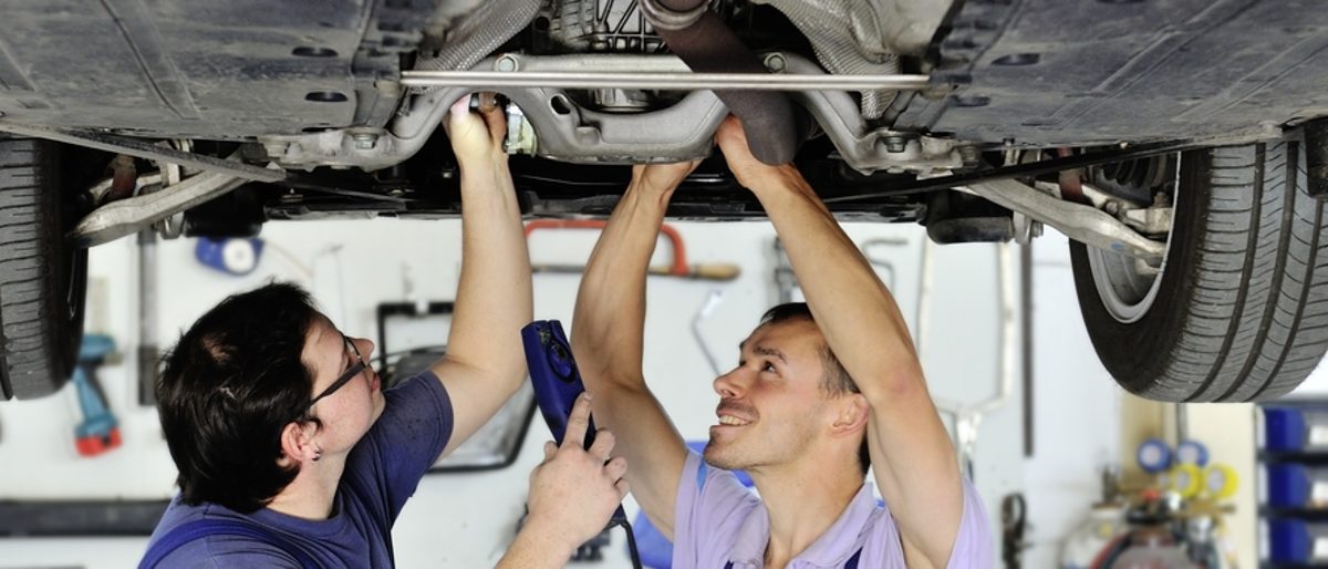 Fördermittel für Hardwarenachrüstungen von Handwerksfahrzeugen nutzen. Auto steht auf Hebebühne, zwei Fahrzeugmechaniker stehen unter dem Auto.