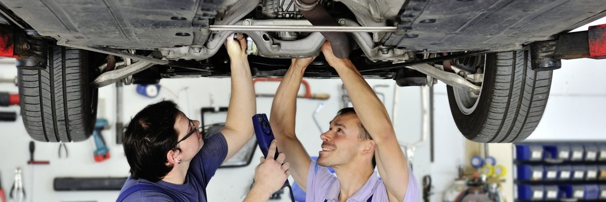 Fördermittel für Hardwarenachrüstungen von Handwerksfahrzeugen nutzen. Auto steht auf Hebebühne, zwei Fahrzeugmechaniker stehen unter dem Auto.