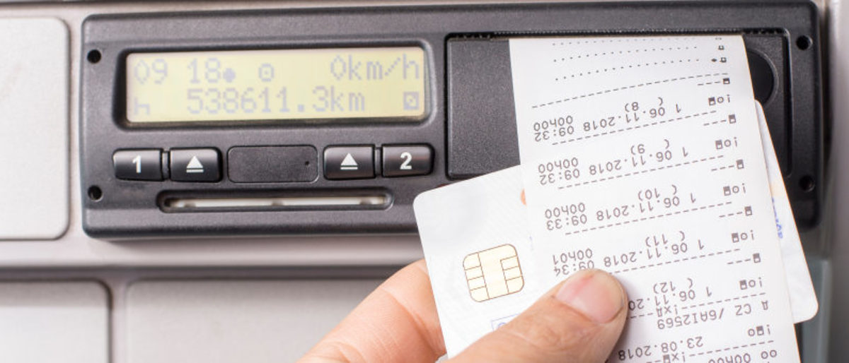 Änderung bei der Fahrtenschreiber-Pflicht im Handwerk. Digitaler Tachograf, Fahrtenschreiber, Fahrer hält Karte und Ausdruck des Fahrenschreibers in der Hand