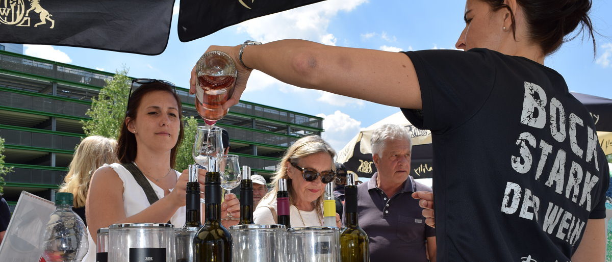 Der Willy-Wein Bockstark kam bei den Besuchern der BUGA gut an. Eine Frau in schwarzem T-Shirt mit Aufschrift schenkt einer anderen Frau Wein in ein Weinglas.