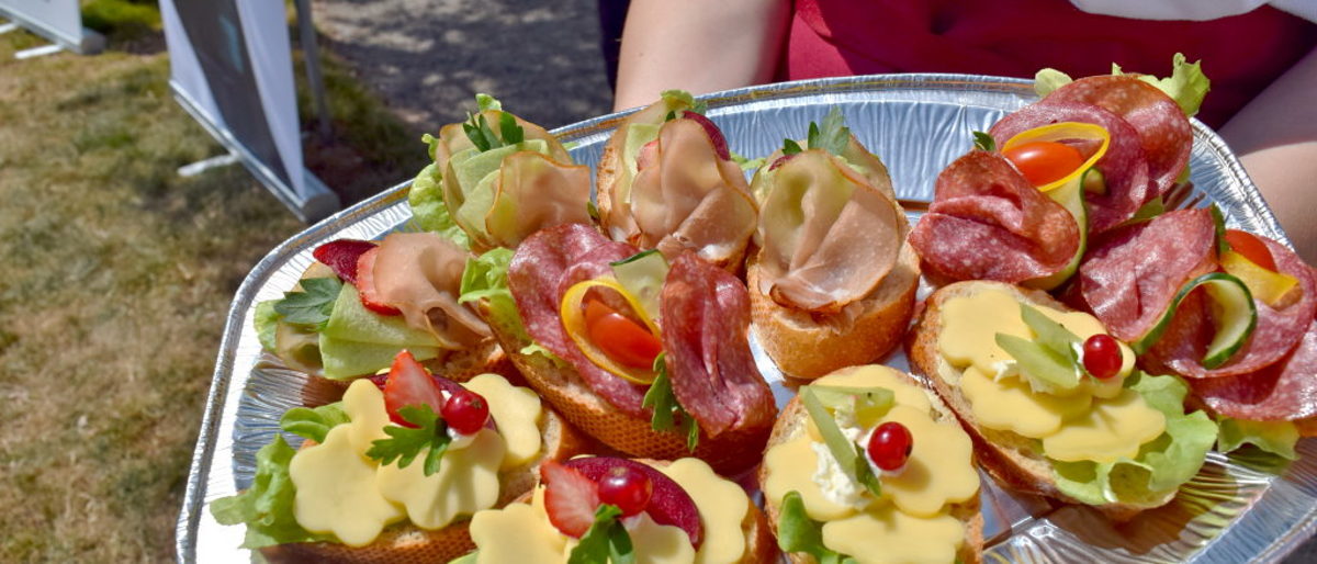Gut vorbereitet: Häppchenplatte mit Wurst aus eigener Herstellung. Baguettescheiben belegt mit Wurst und Käse liegen hübsch dekoriert auf silberner Platte
