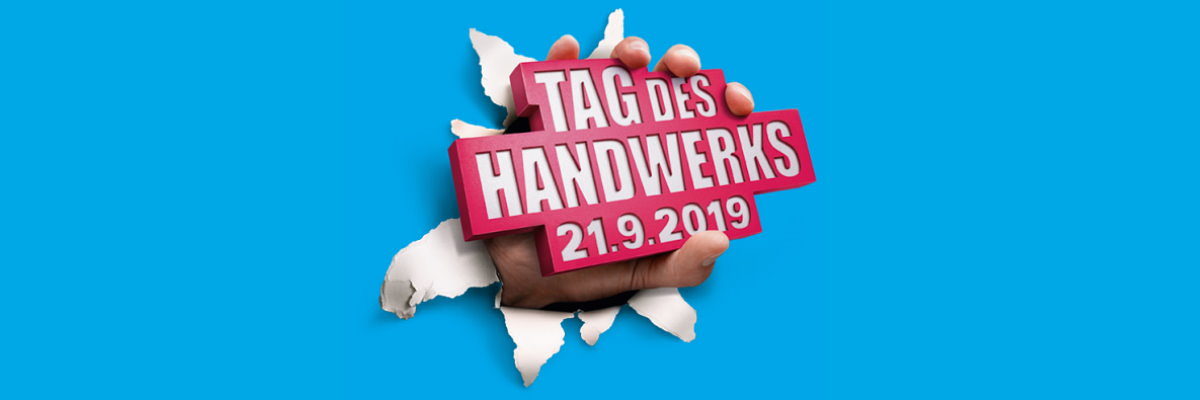 Betriebe können den Tag des Handwerks am 21.9.2019 für Aktionen nutzen Eine Hand hält einen rot-weißen Schriftzug "Tag des Handwerks 21.9.2019" und bricht damit durch eine blaue Fläche.