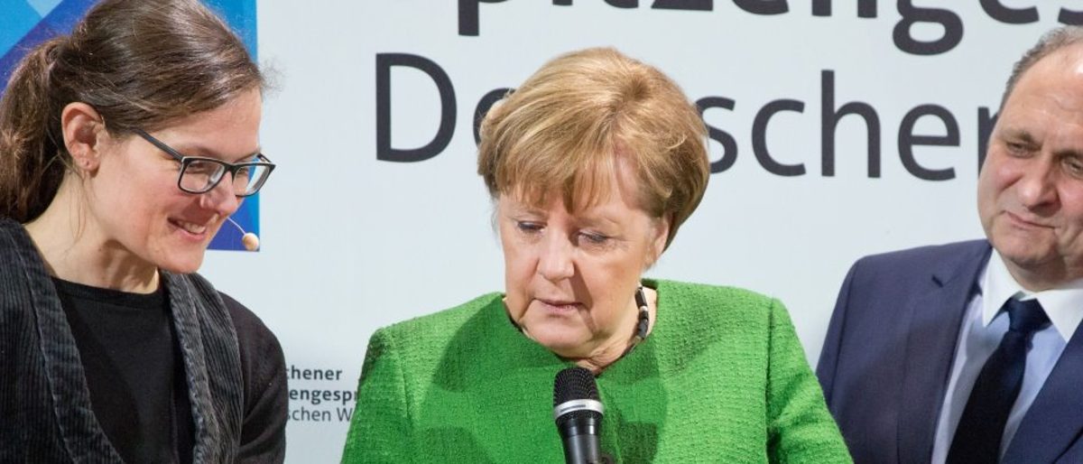 Bundeskanzlerin Angela Merkel (M.) besucht gerne das Handwerk der IHM. Zwei Frau und ein Mann stehen zusammen und betrachten etwas außerhalb des Bildes. Die Frau in der Mitte hält ein Mikrofon.