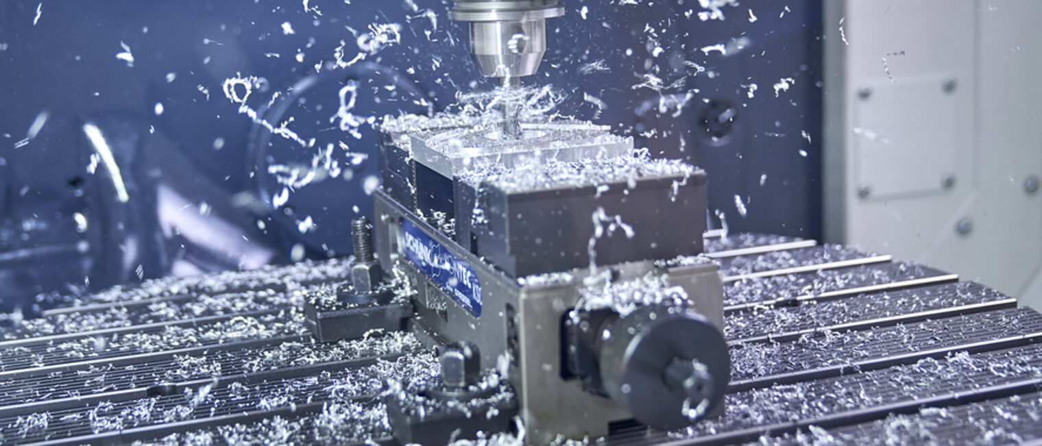 In den meisten Betrieben laufen die Maschinen derzeit auf Hochtouren. Blick in eine CNC-Maschine: Ein Bohrer fräst gerade ein Stück Metall. Dabei fliegen viele Metallspäne umher.