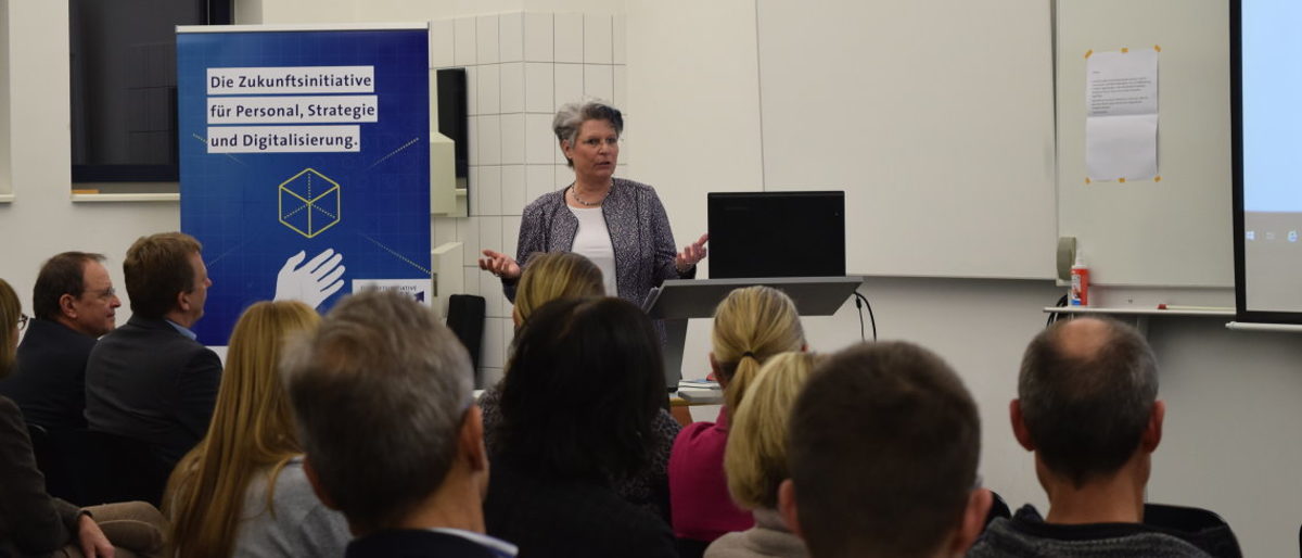 Angela Wosylus, sprach über die wachsende Bedeutung von Social Media Referentin steht vor Publikum und hält einen Vortrag