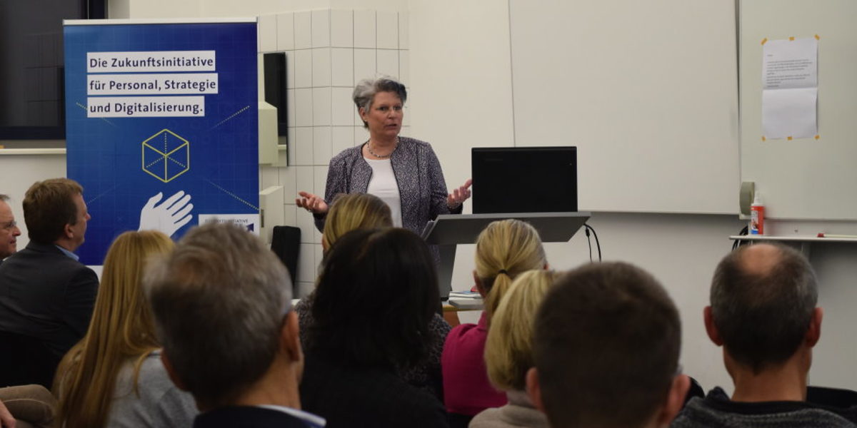 Angela Wosylus, sprach über die wachsende Bedeutung von Social Media Referentin steht vor Publikum und hält einen Vortrag
