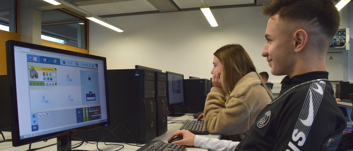 Schüler können am Wettbewerb des Online-Spiels Meisterpower teilnehmen Ein Junge und ein Mädchen sitzen konzentriert vor Computerbildschirmen in einen Klassenzimmer.