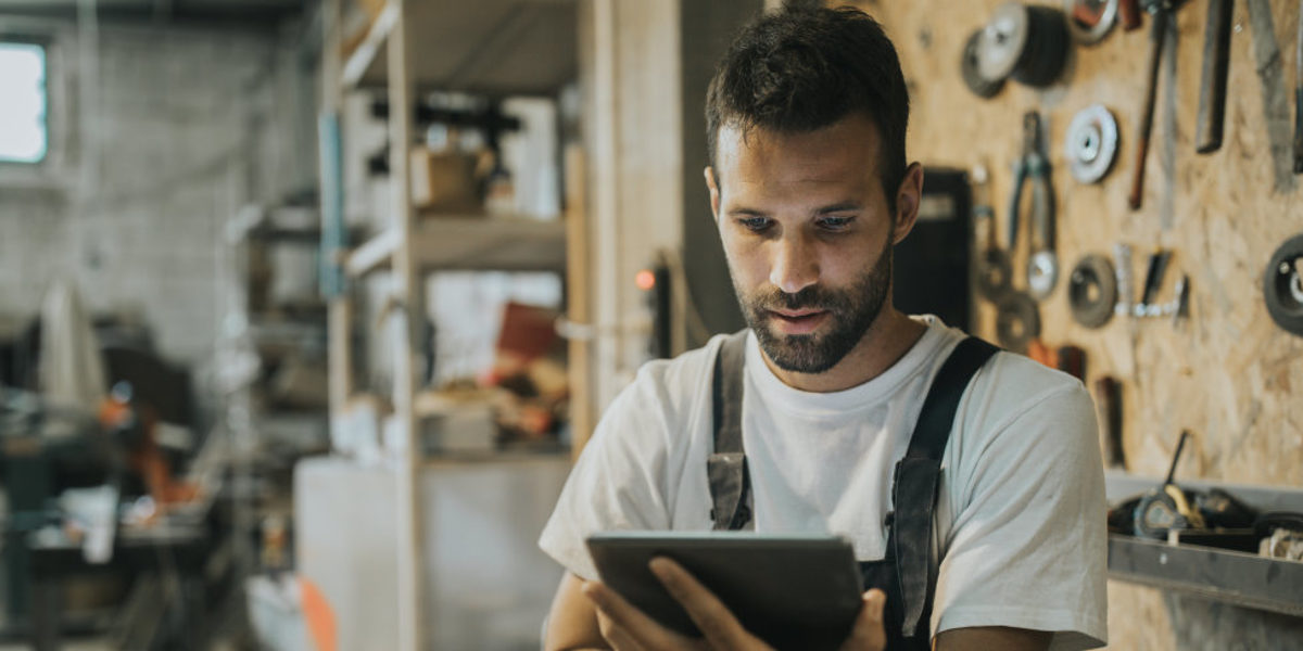 Web-Seminare für Handwerker - kostenfrei und wo Sie wollen. Handwerker in Werkstatt mit Tablet in der Hand, schaut Web-Seminar