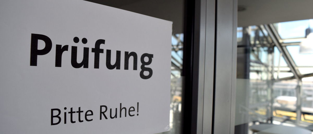 Aktuelle Informationen zu Kursen und Prüfungsterminen im Handwerk. An einer Glastür ist ein Zettel mit der Aufschrift "Prüfung Bitte Ruhe" aufgeklebt.