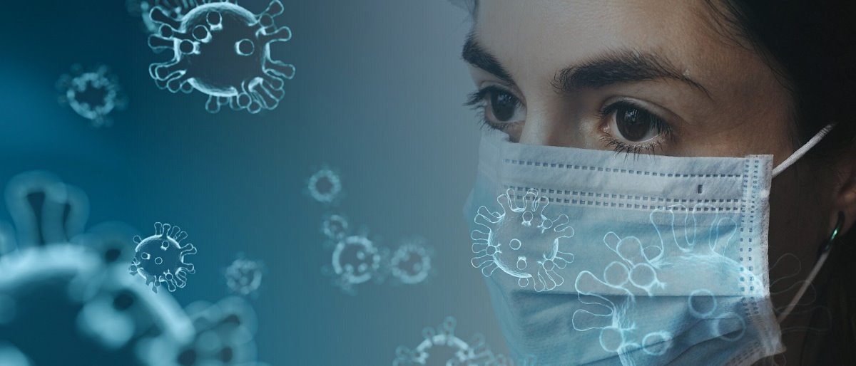 Handwerksbetriebe brauchen mehr Informationen zu Schutzmaßnahmen. Eine Frau mit Schutzmaske und ernstem Blick ist am rechten Bildrand zu sehen. Im Hintergrund Darstellungen des Coronavirus.