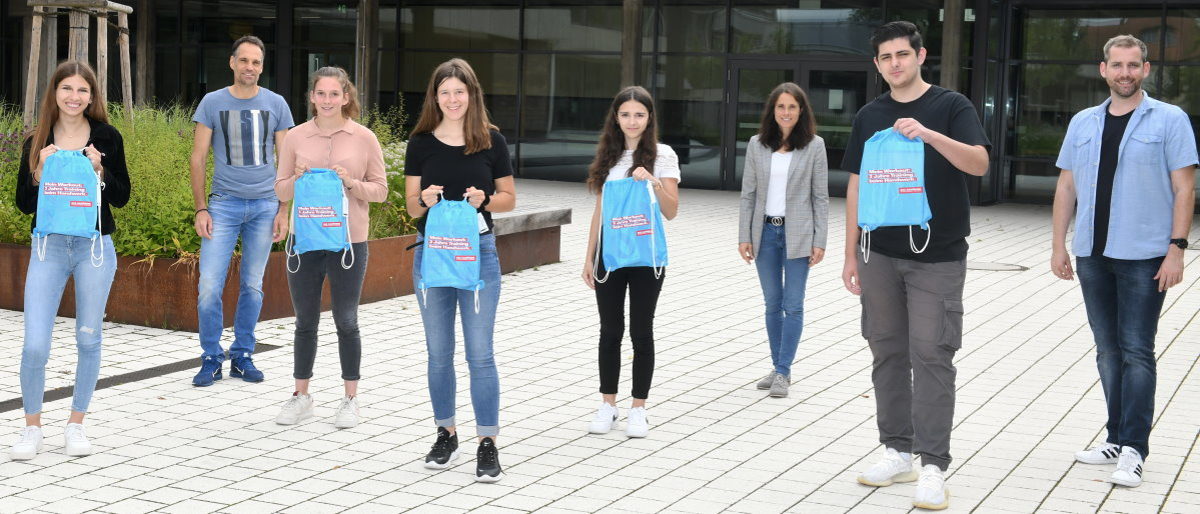 Gewinner der Otto-Klenert-Schule mit Lehrern und Rektorin (3.v.r.). Fünf Schüler und drei Lehrer stehen mit Abstand zueinander im Schulhof. Die Schüler halten alle blaue Turnbeutel hoch.