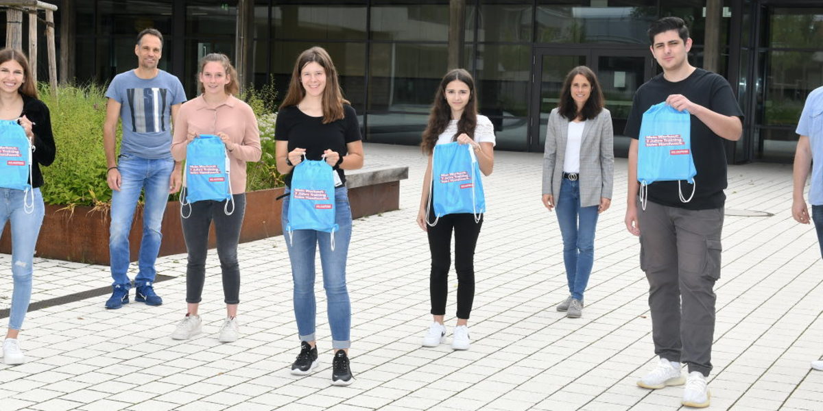 Gewinner der Otto-Klenert-Schule mit Lehrern und Rektorin (3.v.r.). Fünf Schüler und drei Lehrer stehen mit Abstand zueinander im Schulhof. Die Schüler halten alle blaue Turnbeutel hoch.