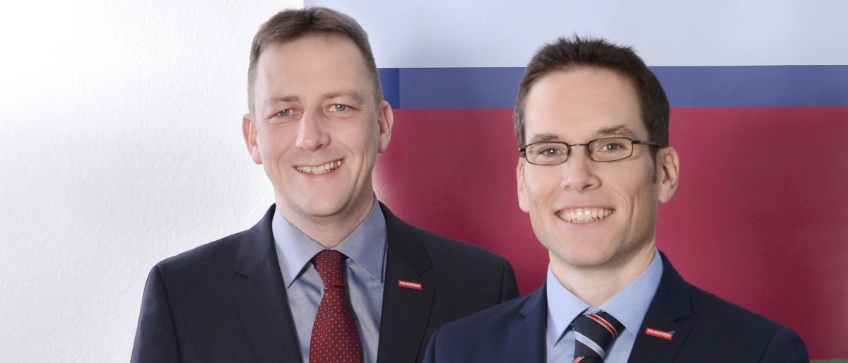 Hauptgeschäftsführer Ralf Schnörr (l.), Stellvertreter Achim Hofmann. Zwei Männer lächeln in die Kamera. Nur Ihre Köpfe, Hals und Schultern sind zu sehen. Sie tragen Sakko, Hemd und Krawatte.