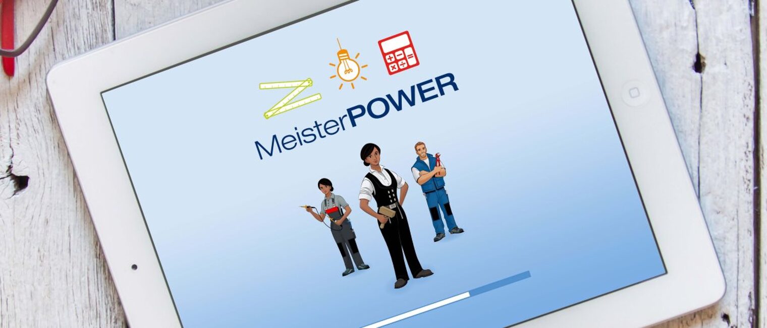 Das Lernspiel Meisterpower ist ideal für den Einsatz im Fernunterricht. Ein weißes Tablet liegt auf einem Untergrund aus weißem Holz. Auf dem Bildschirm steht Meisterpower, darunter drei Figuren.